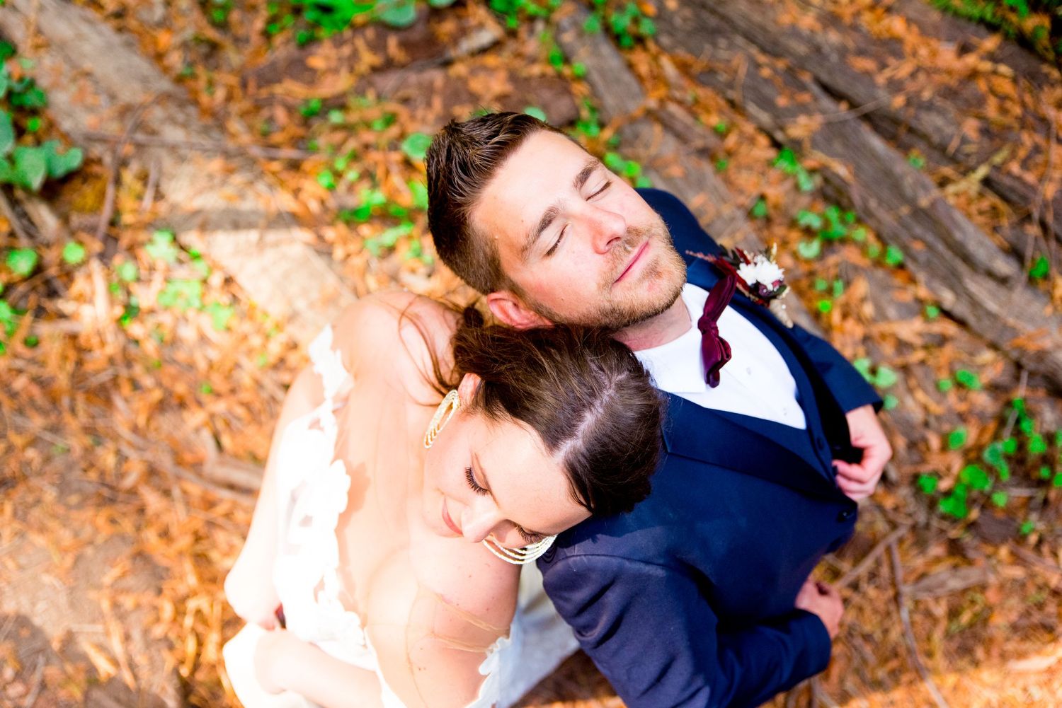bride and groom lay heads on each other with eyes closed in the Northern California Redwoods on wedding day