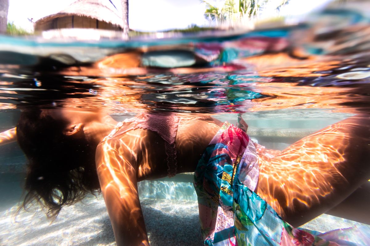 A woman lying in the pool wearing a skirt