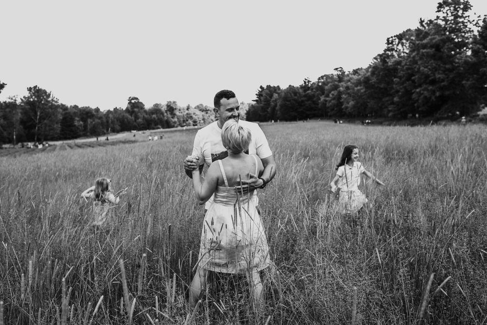 un couple qui danse dans un pré avec leur deux enfants qui courent autour d'eux