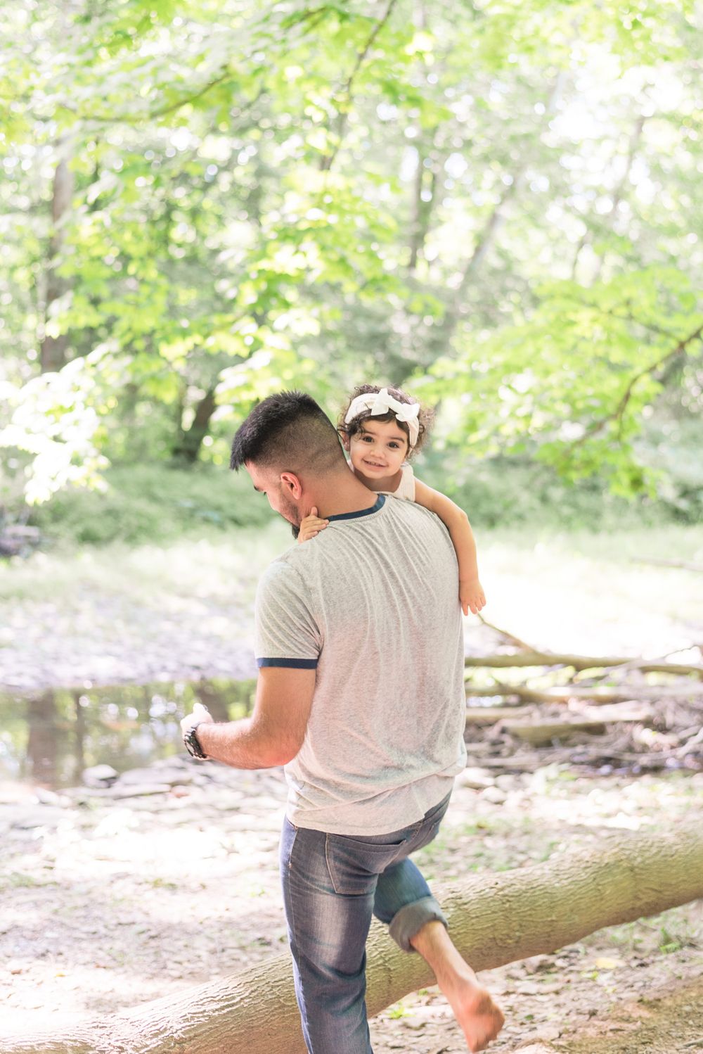 Dad holding toddler over shoulder in creek in Pittsburgh, Pennsylvania