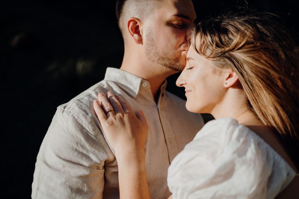 An intimate portrait of a couple sharing a tender moment against a dark background.