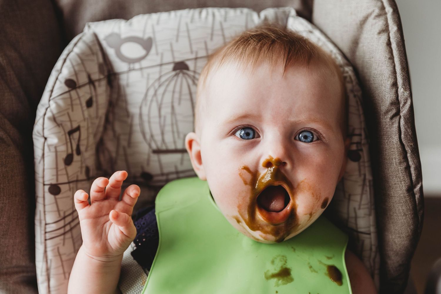 baby girl wearing green bib eating puree