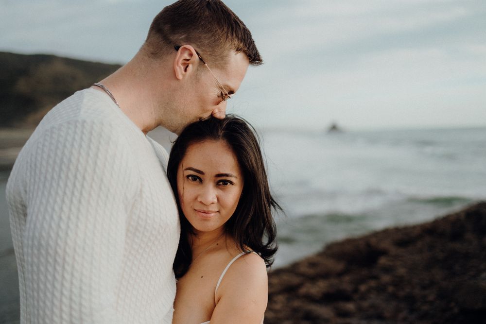 A tender moment between a couple on a cloudy day at the beach.
