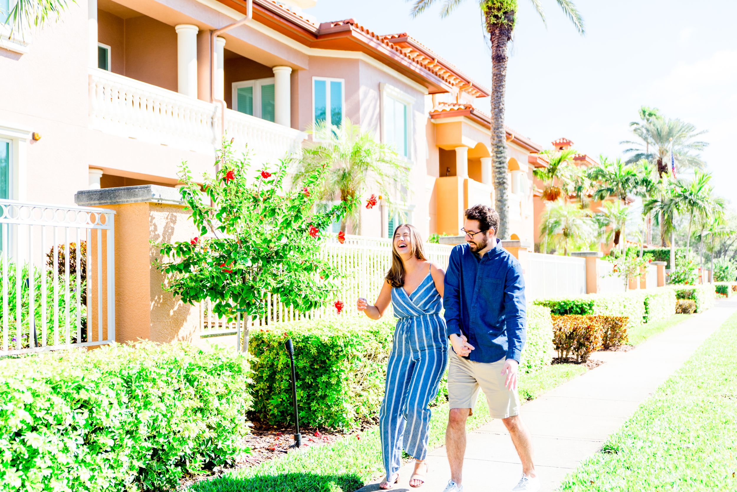 young couple in blue outfits walking and laughing at Vinoy Park St Pete engagement photos