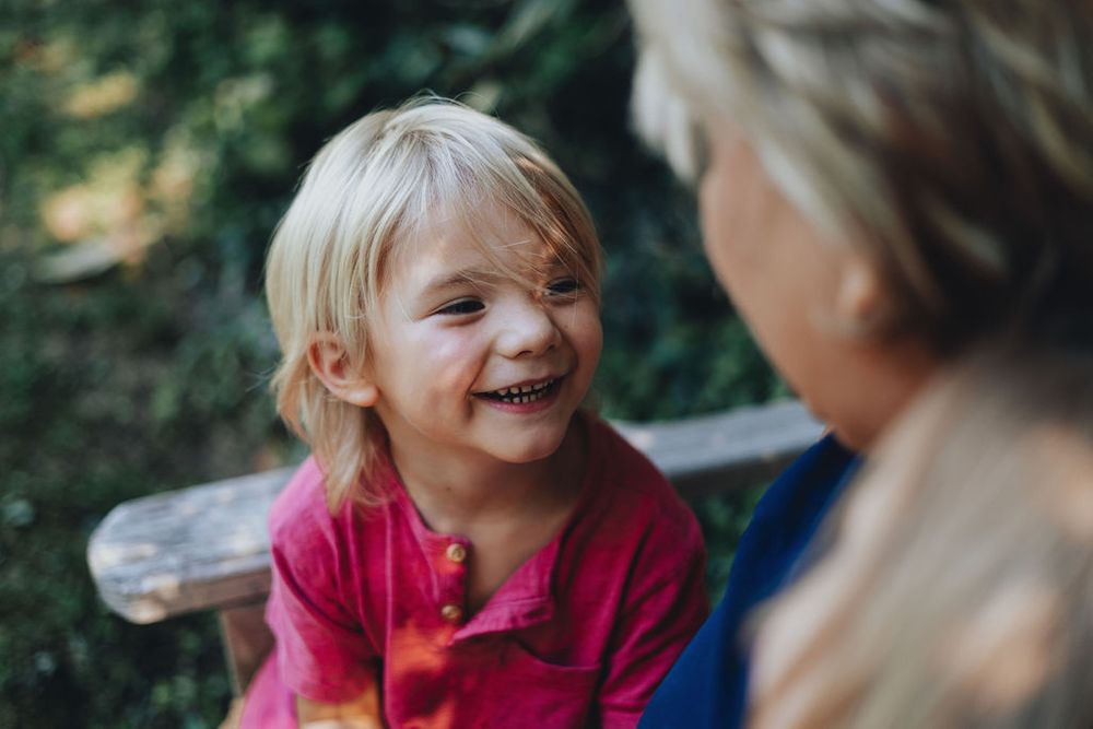 Grandson smiles as grandmother while sitting on the bench in the garden behind Sayen House at Sayen Garden, New Jersey