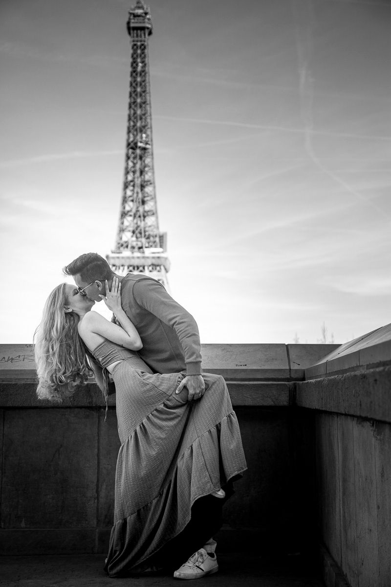 Romantic couple embraces in black and white photo with iconic Eiffel Tower silhouette in Paris.