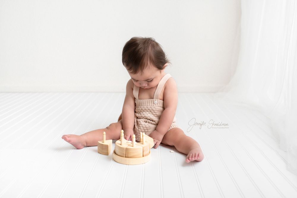 Baby Elijah looks down at his wooden toy cake during his photo session in Colorado Springs,