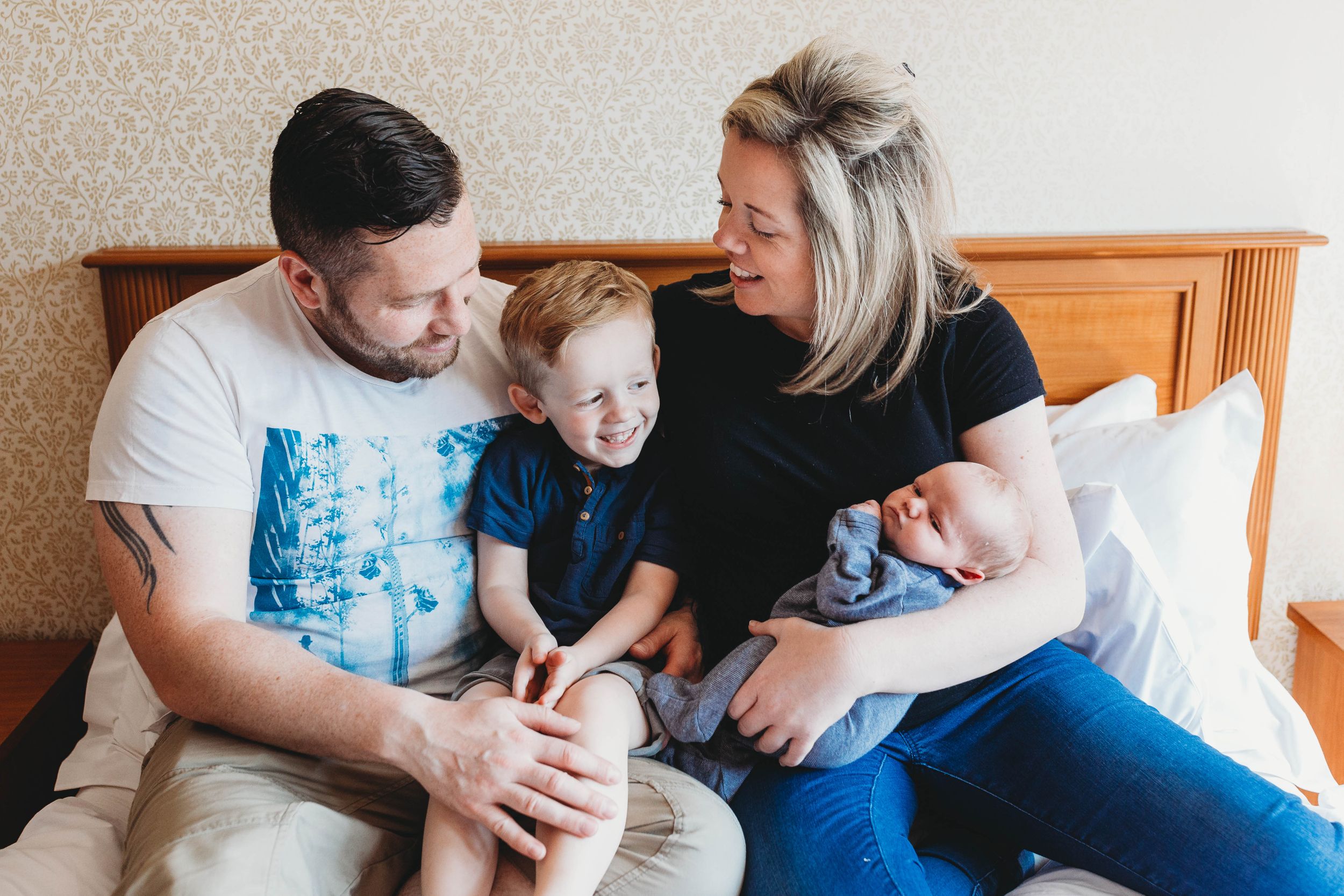 family of four sitting on bed big brother little brother