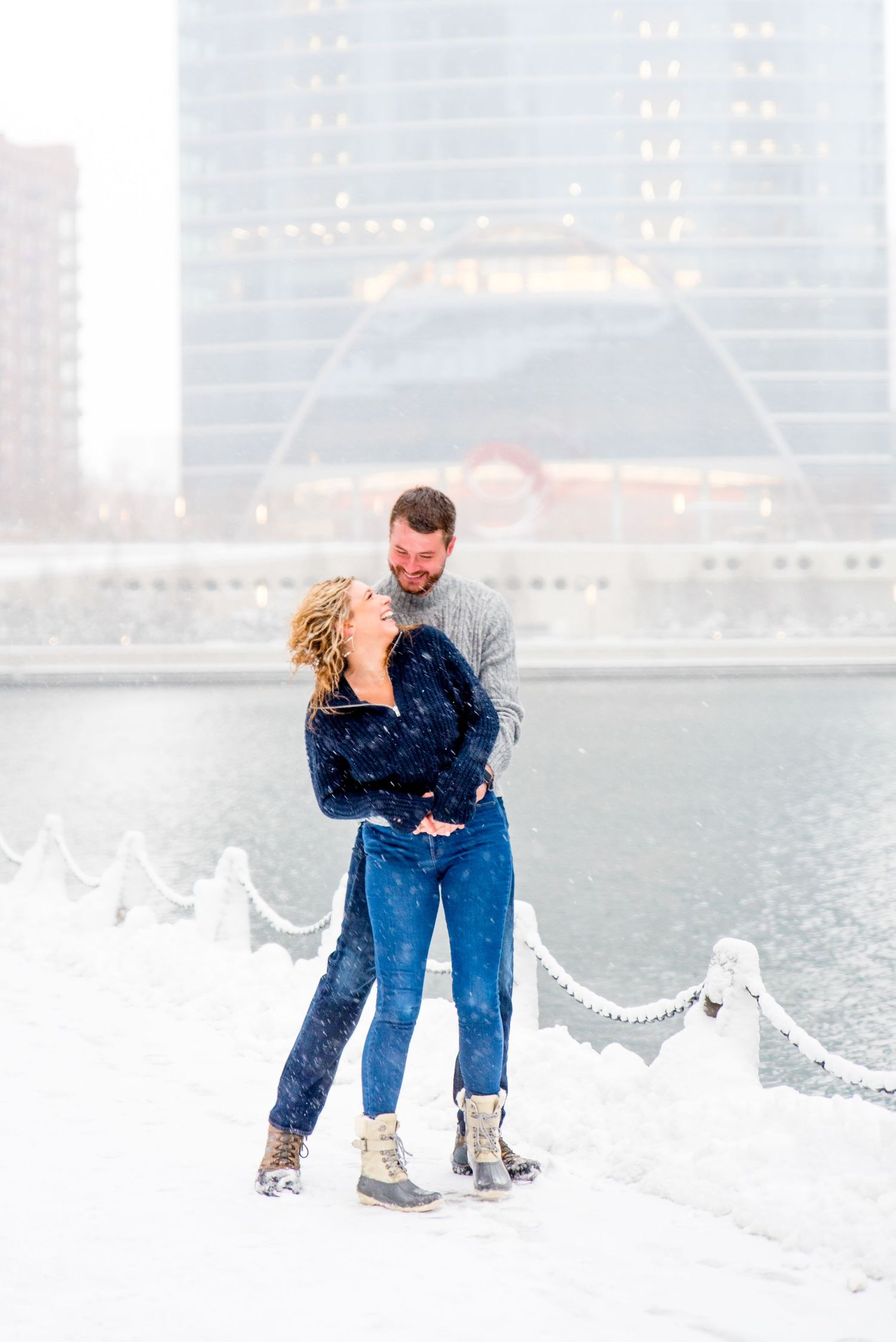 man and woman in navy and grey sweaters smiling in snow at Wolf Point Chicago