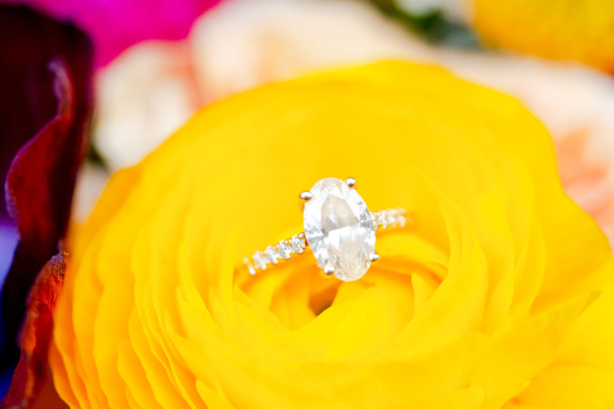 oval diamond engagement ring in a yellow ranunculus flower