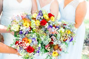 bridesmaids in light blue holding their colorful rainbow wedding bouquets together for a summer wedding in Chicago