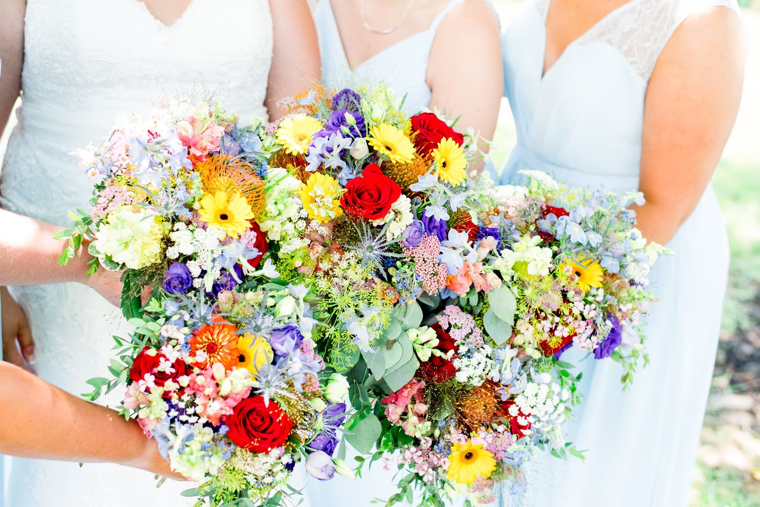 bridesmaids in light blue holding their colorful rainbow wedding bouquets together for a summer wedding in Chicago