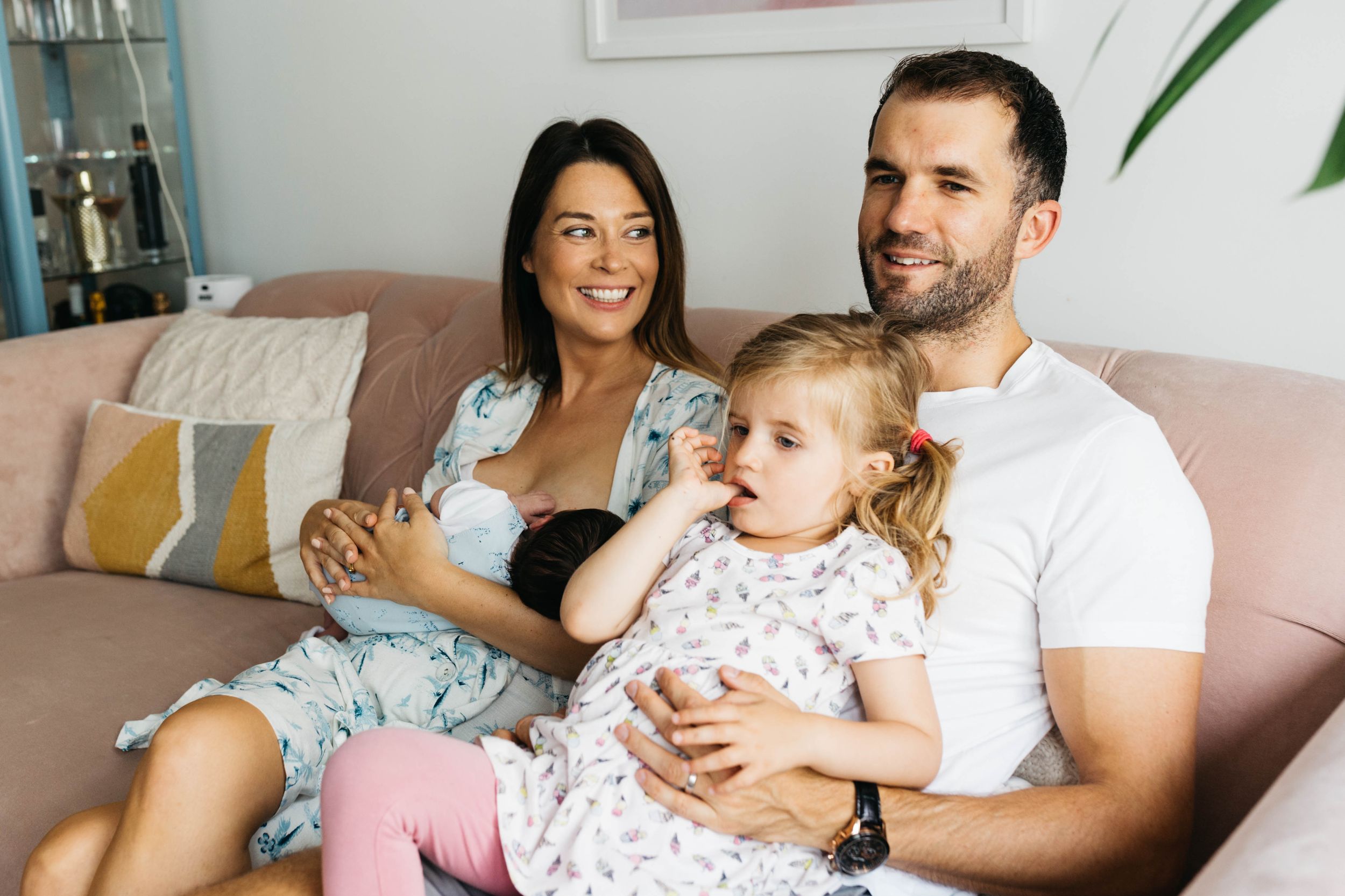 mum looking adoringly at dad with two kids on sofa