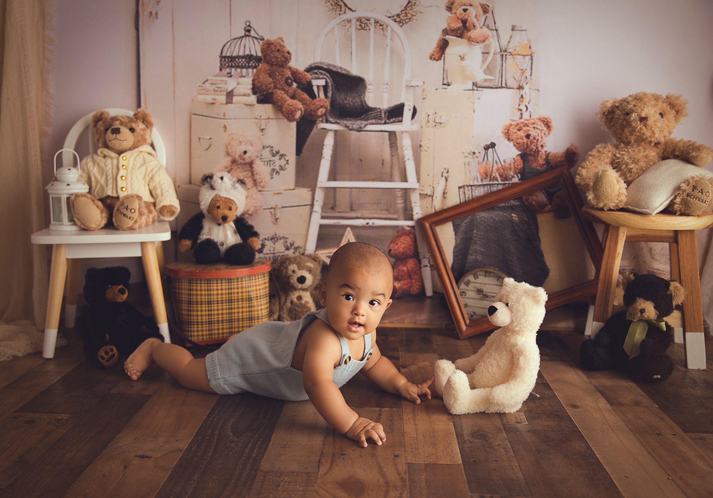 7 month old laying on floor with Teddy bear at his side wood floor