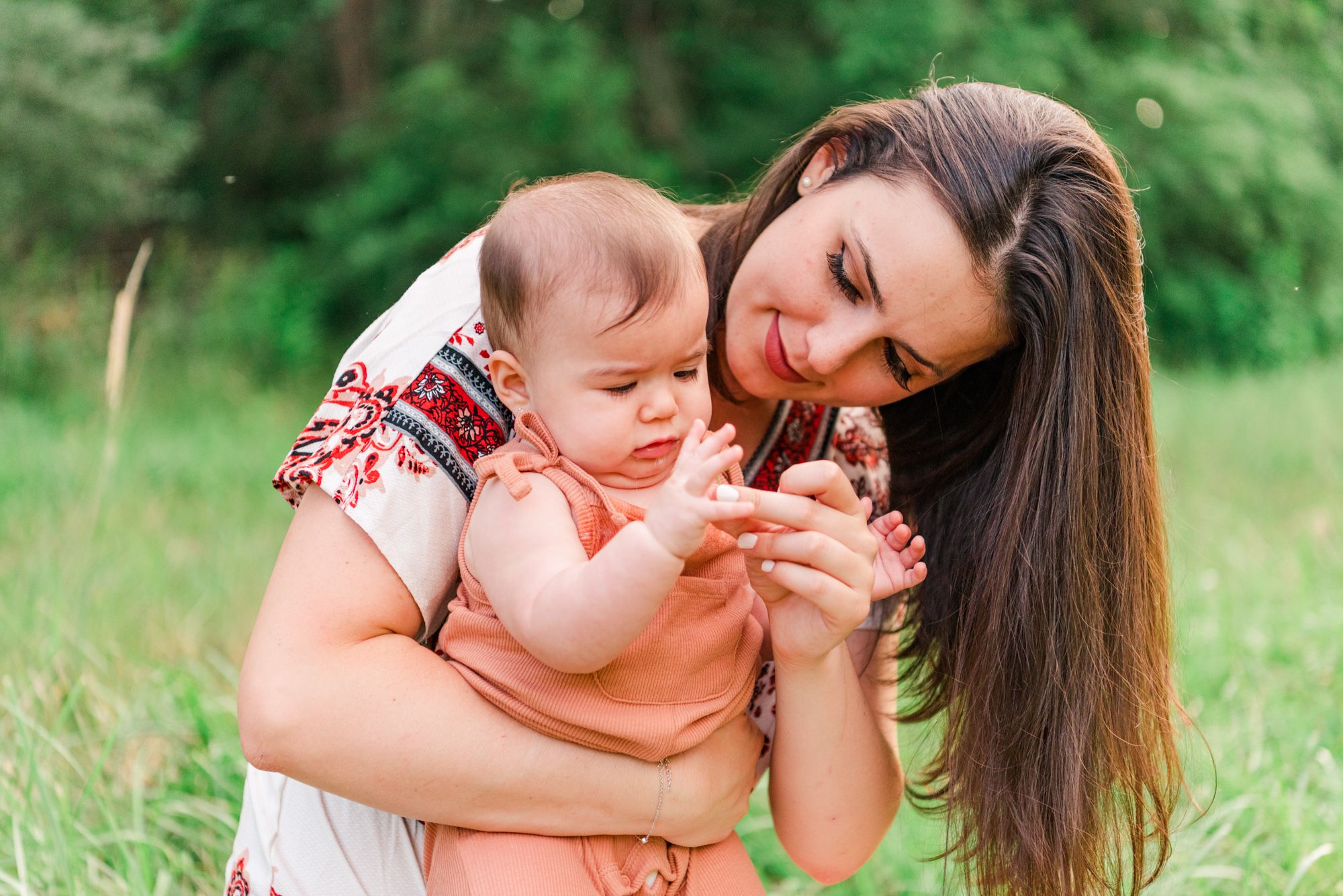 Mother holding 6-month-old baby in her lap and looking at flowers in Pittsburgh, Pennsylvania