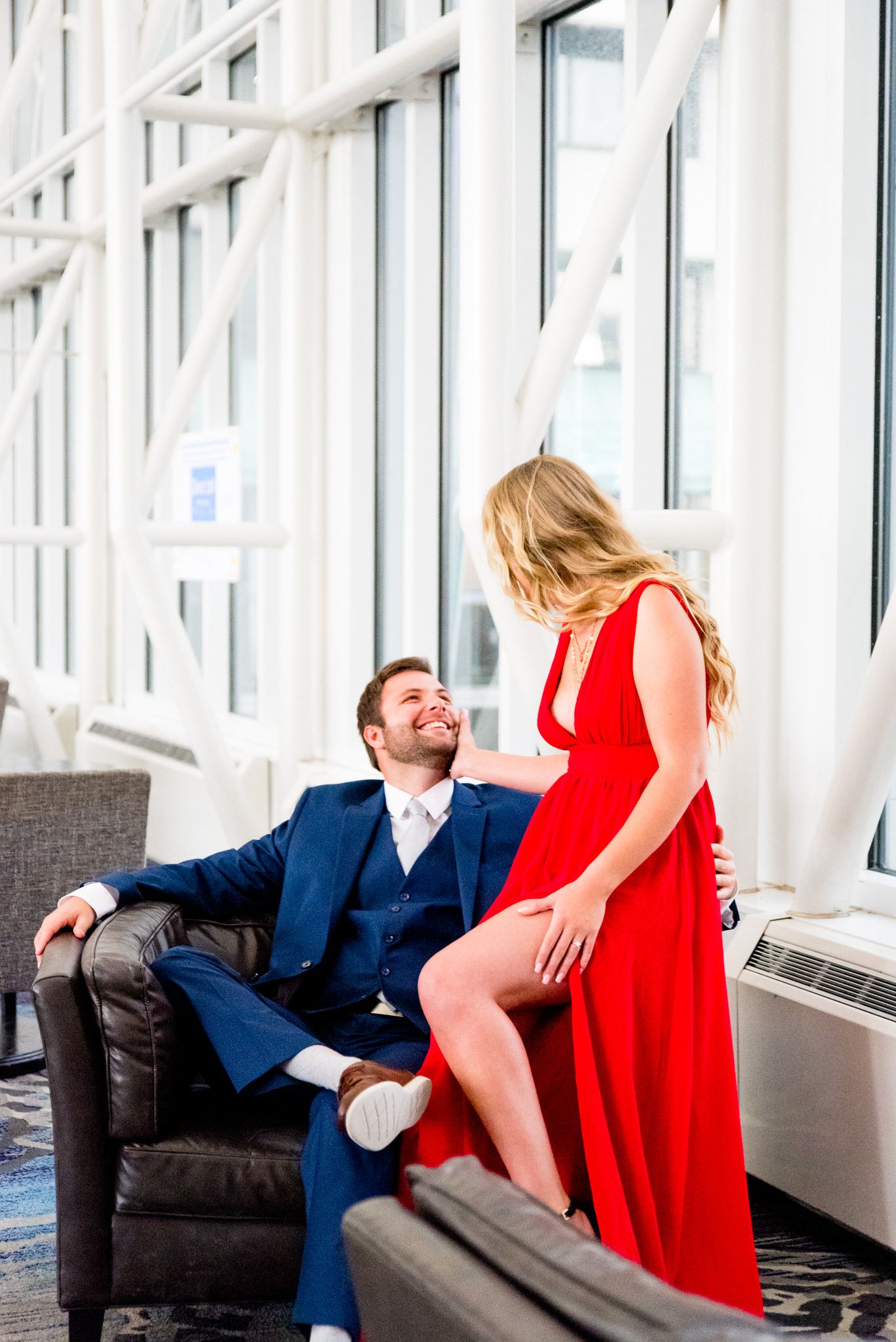 blonde woman in red dress laughing with fiance in navy suit at Galt House Hotel engagement pictures