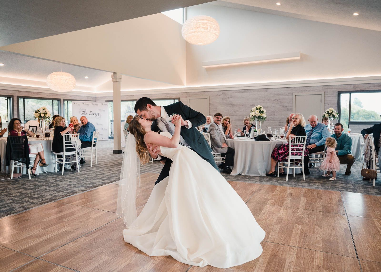 groom dips and kisses bride during their first dance to start the wedding reception