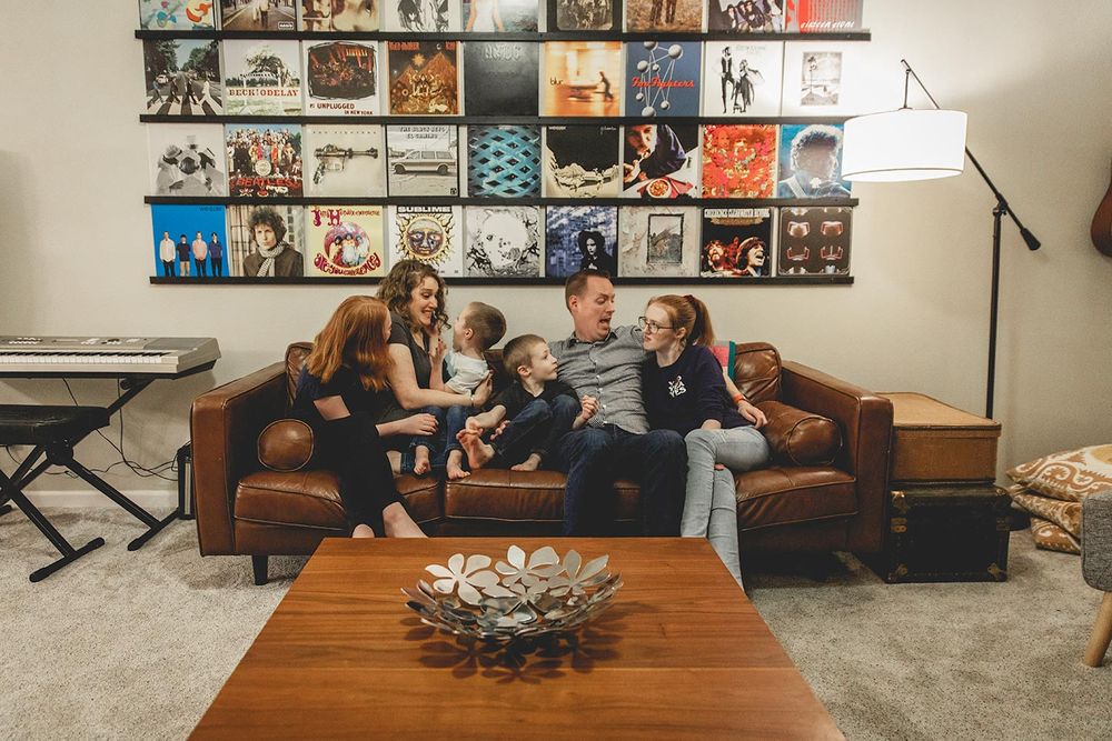 family of six sitting on their couch in their family room that has record albums hung on the wall