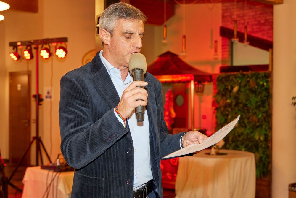Man in business attire speaking into microphone at formal event.
