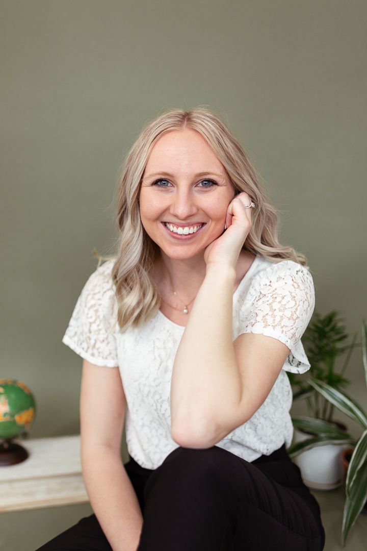 Senior in a studio space smiling at the camera. Green background.