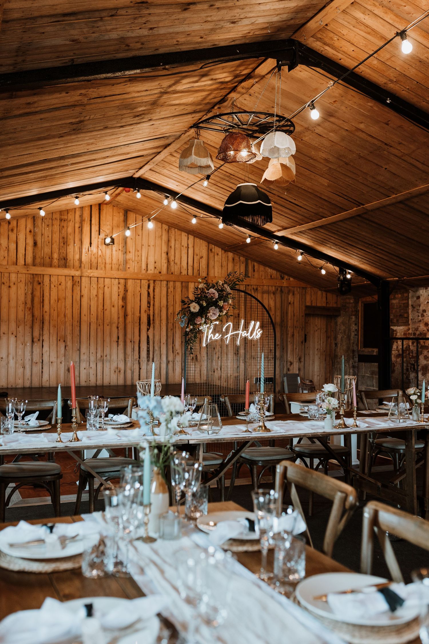 Rustic wooden barn wedding reception setup with elegant table settings and string lights illuminating the vaulted ceiling.