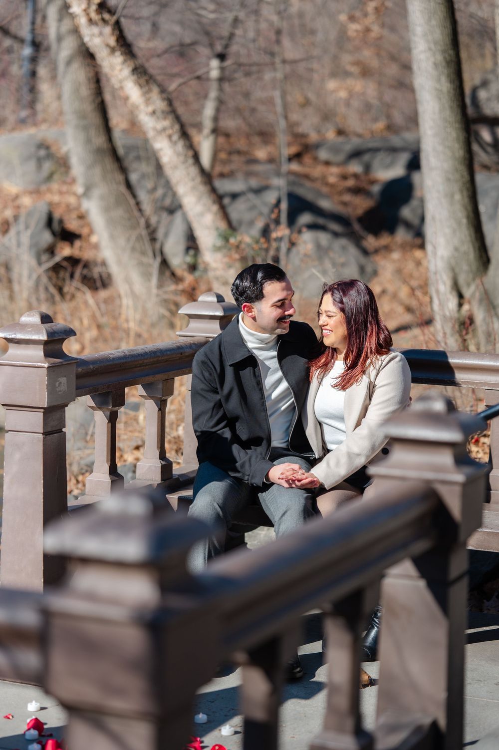 A couple sharing an intimate moment while sitting together on a park bench in Central Park after proposal