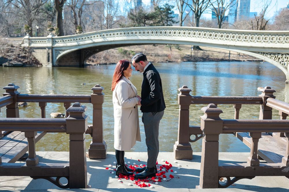 Groom-to-be proposing in front of Bow Bridge during surprise Central Park engagement