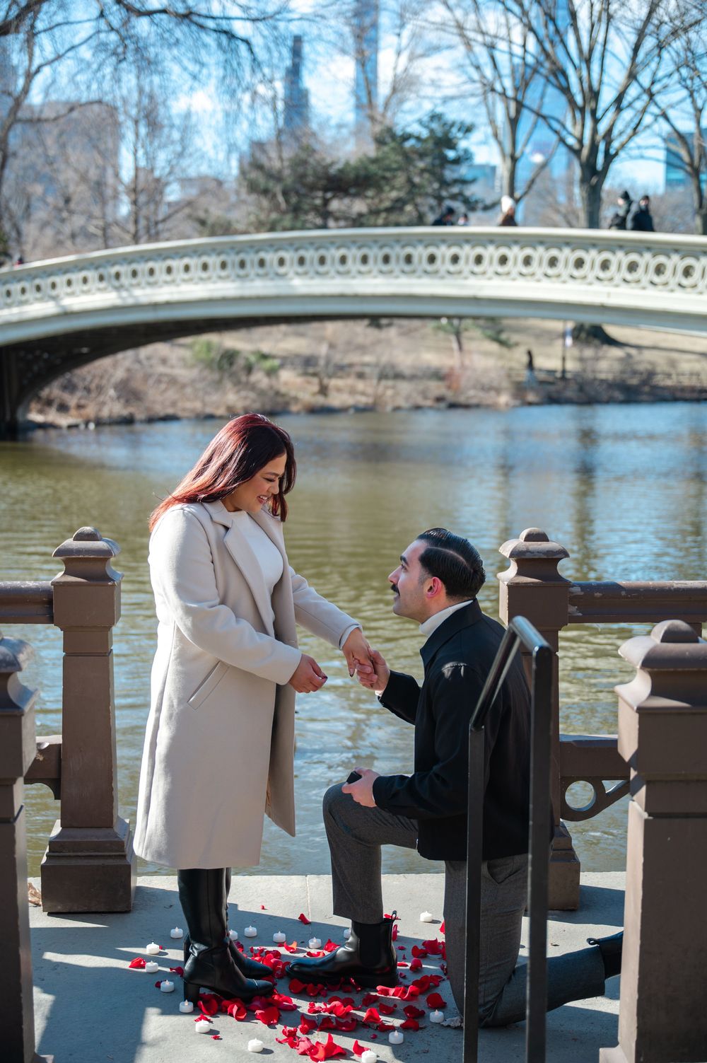 A proposal scene with rose petals scattered near Bow Bridge in Central Park.