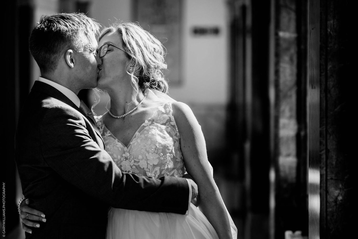 A romantic black and white wedding photograph of a couple sharing a tender kiss.