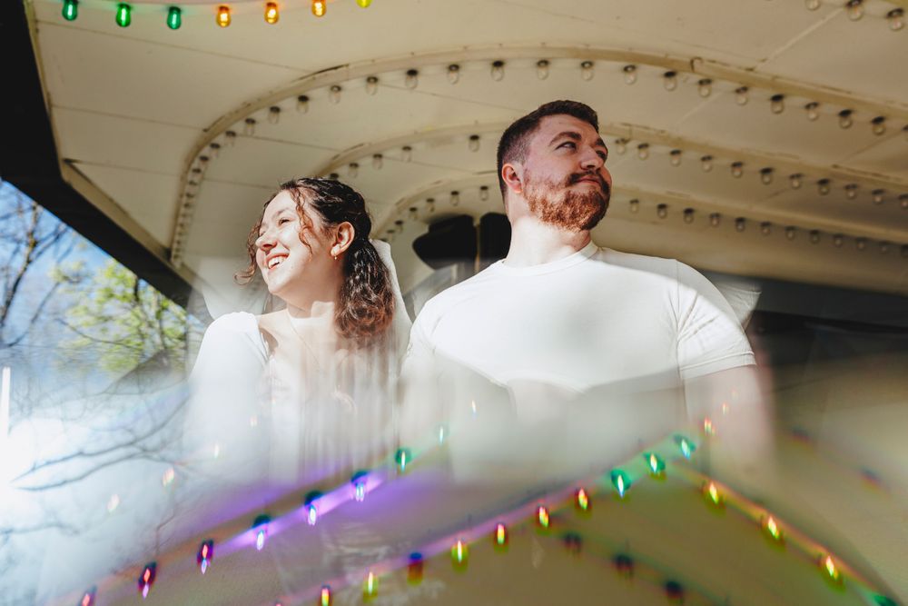 Wedding couple sharing a joyful candid moment under decorative lights and architecture.