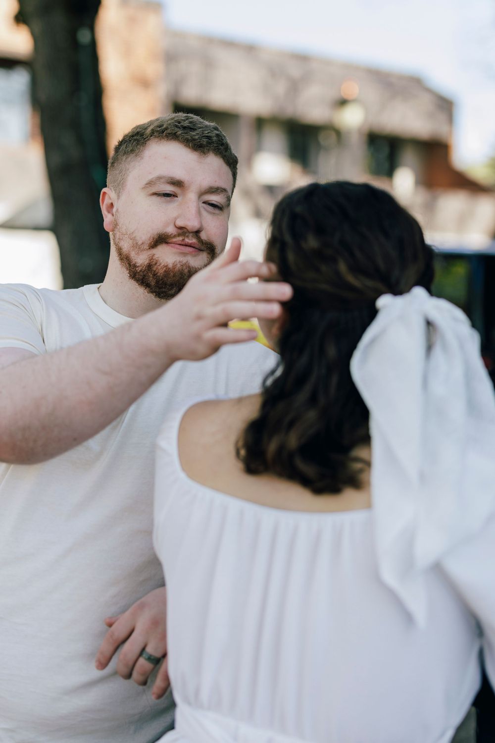A couple shares an intimate moment during their engagement photoshoot outdoors.