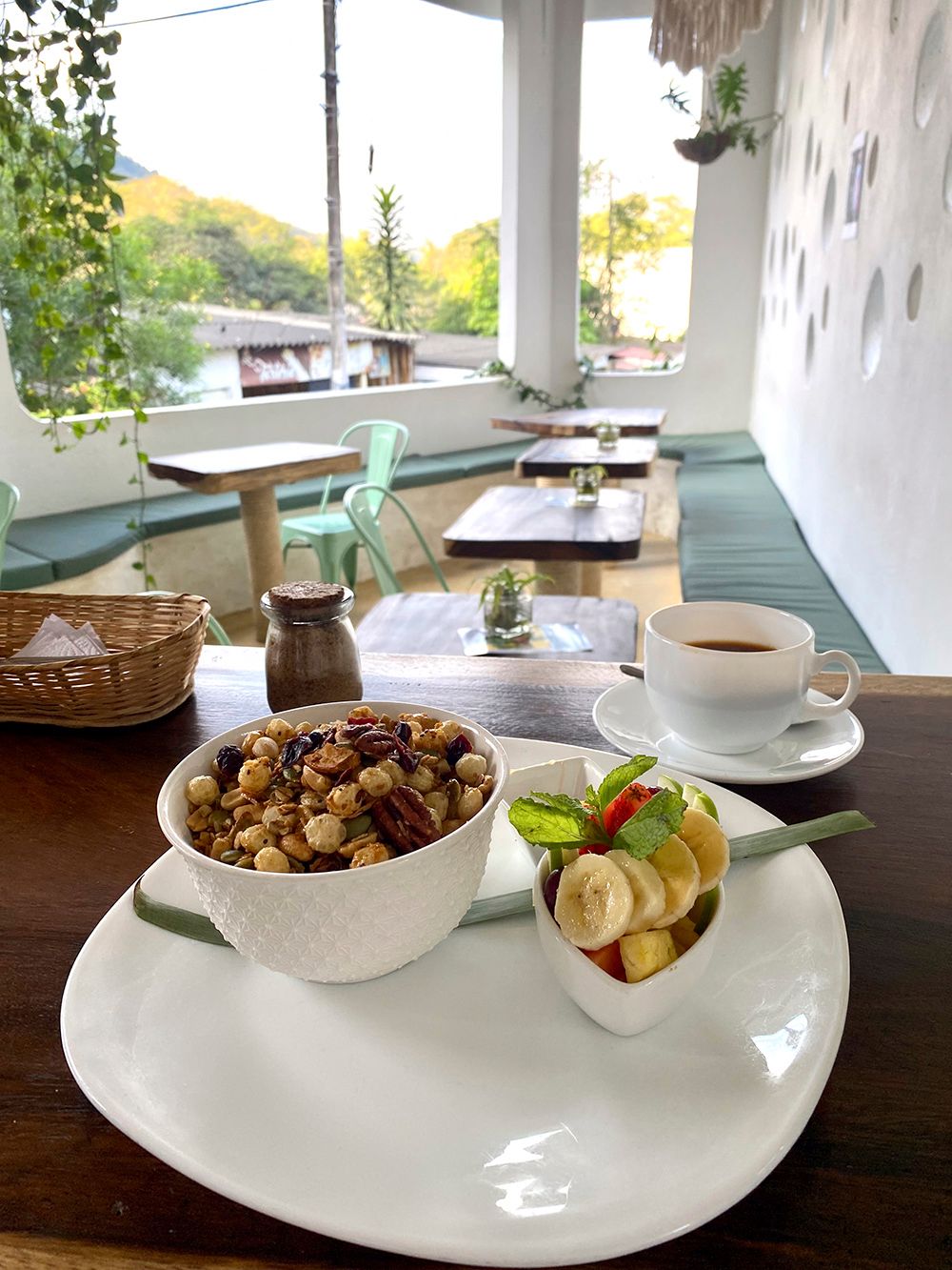 A restaurant table filled with a bowl of breakfast cereals and coffee