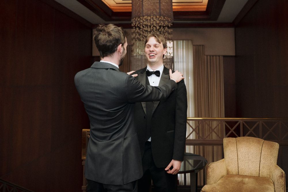 Two people adjusting formal attire before wedding ceremony.