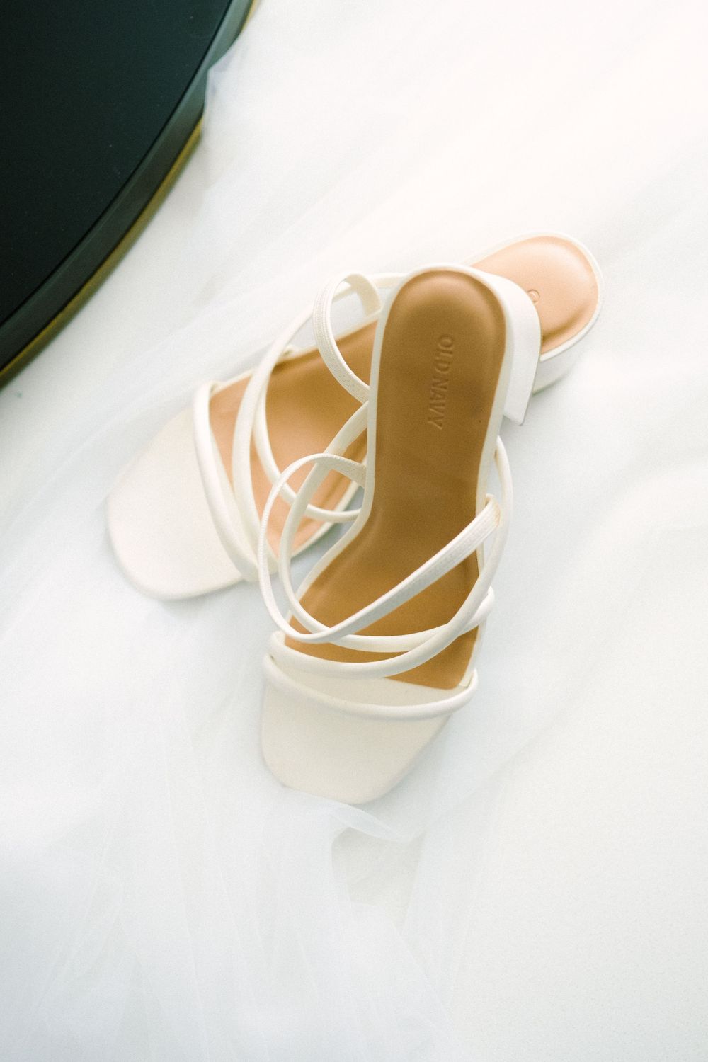 White strappy bridal sandals photographed on light background.