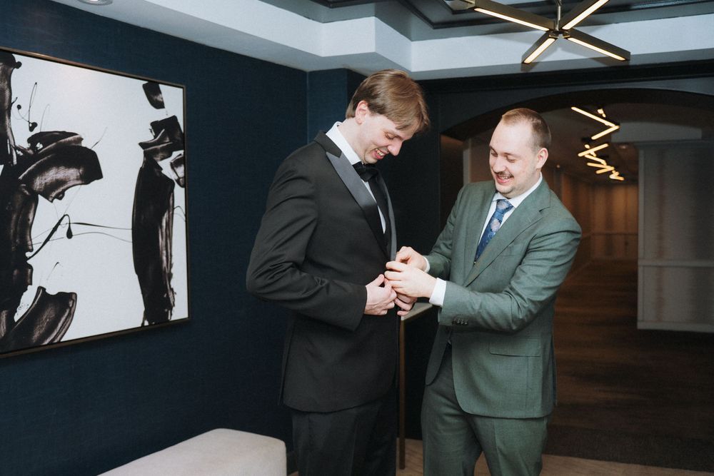 Two people in formal suits sharing a moment in an elegant room with modern decor.