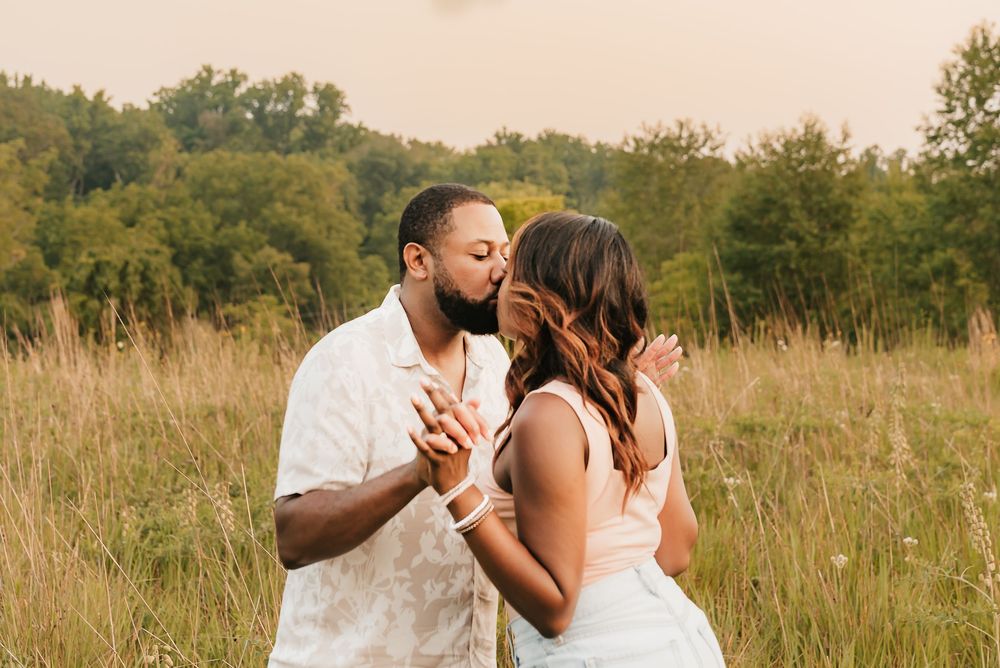 husband and wife kiss in summer field