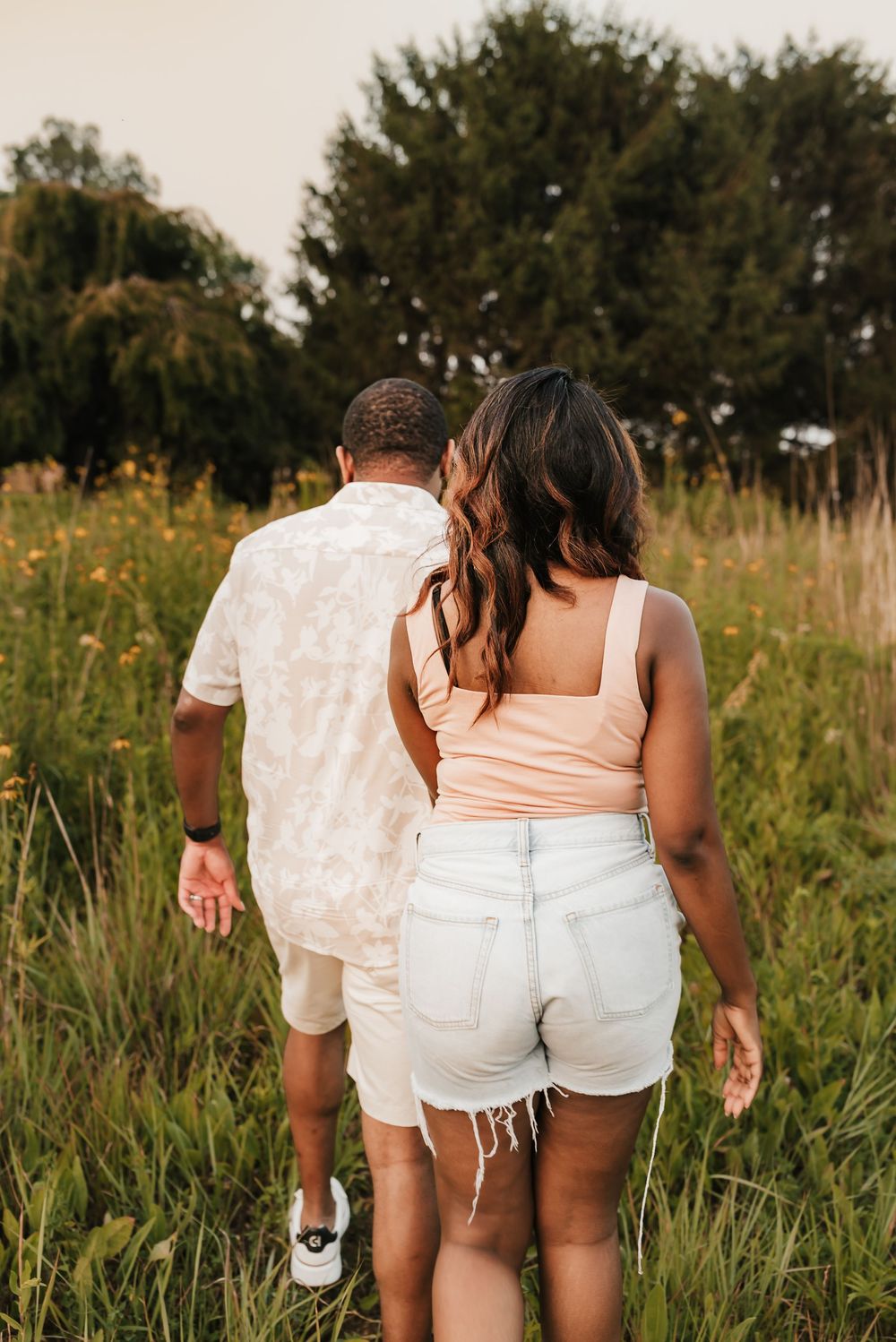 man holds hand and leads her through sunflower field
