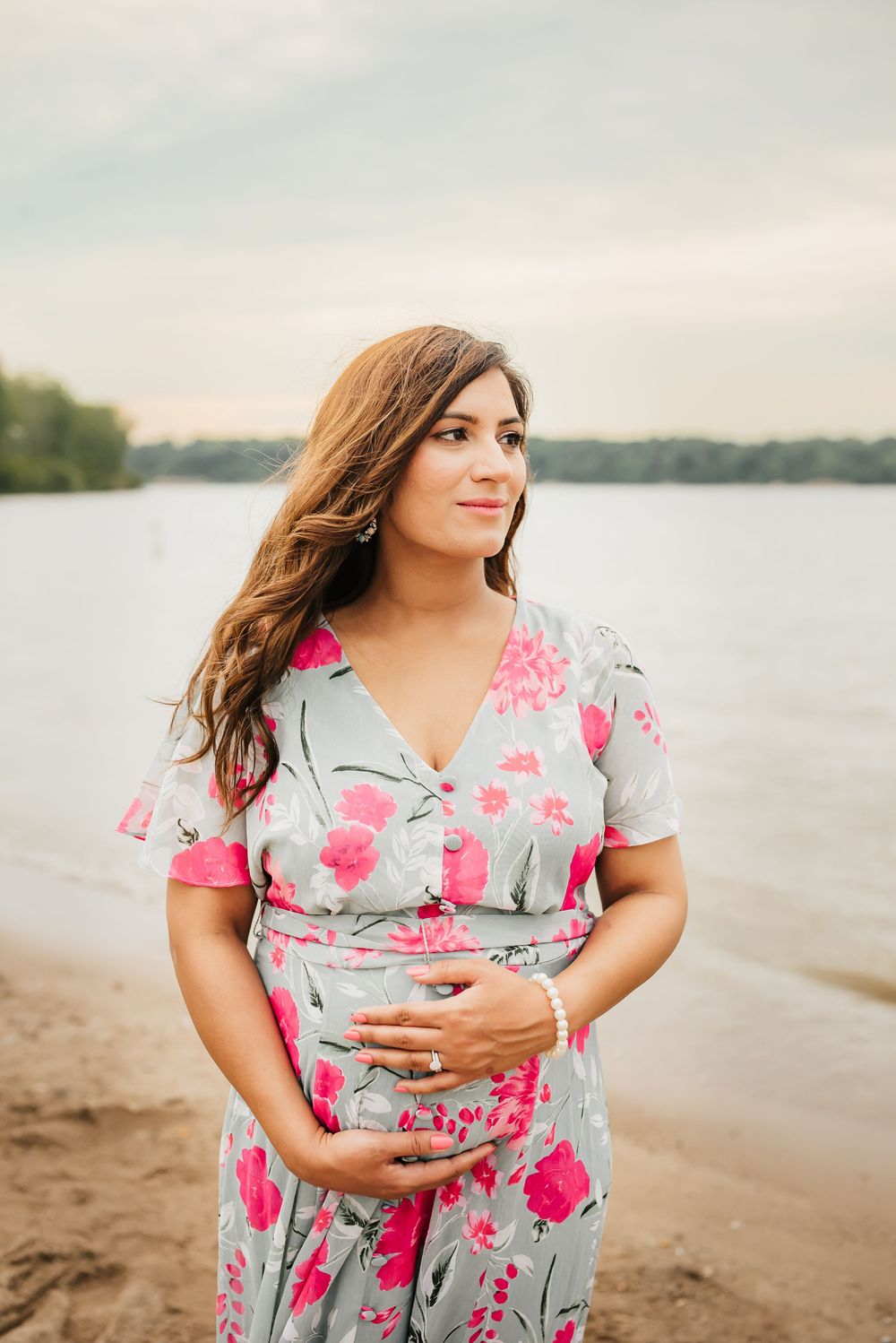 stunning mama to be holds her belly as she looks out at the water