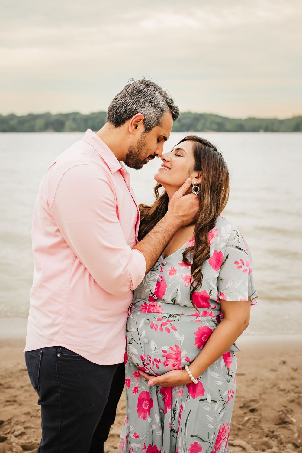 husband tenderly goes in for a kiss as his pregnant wife holds her belly