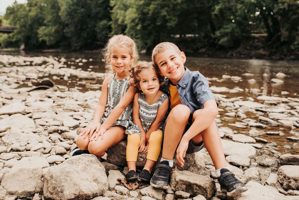siblings hangout on the rocks near the river for family photos in cincinnati, ohio