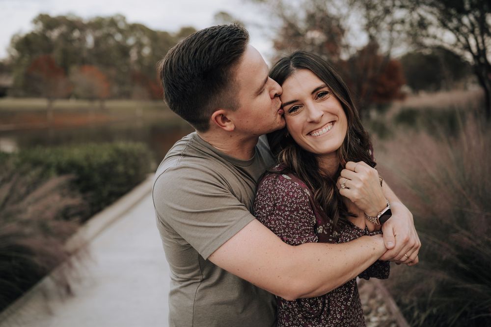 A couple shares an intimate embrace outdoors during a romantic golden hour photoshoot in a natural setting.