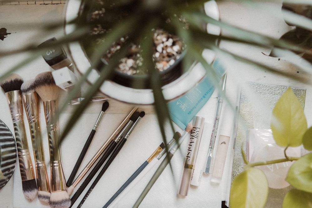 A collection of art brushes and painting supplies arranged on a table with a teal colored item in view.