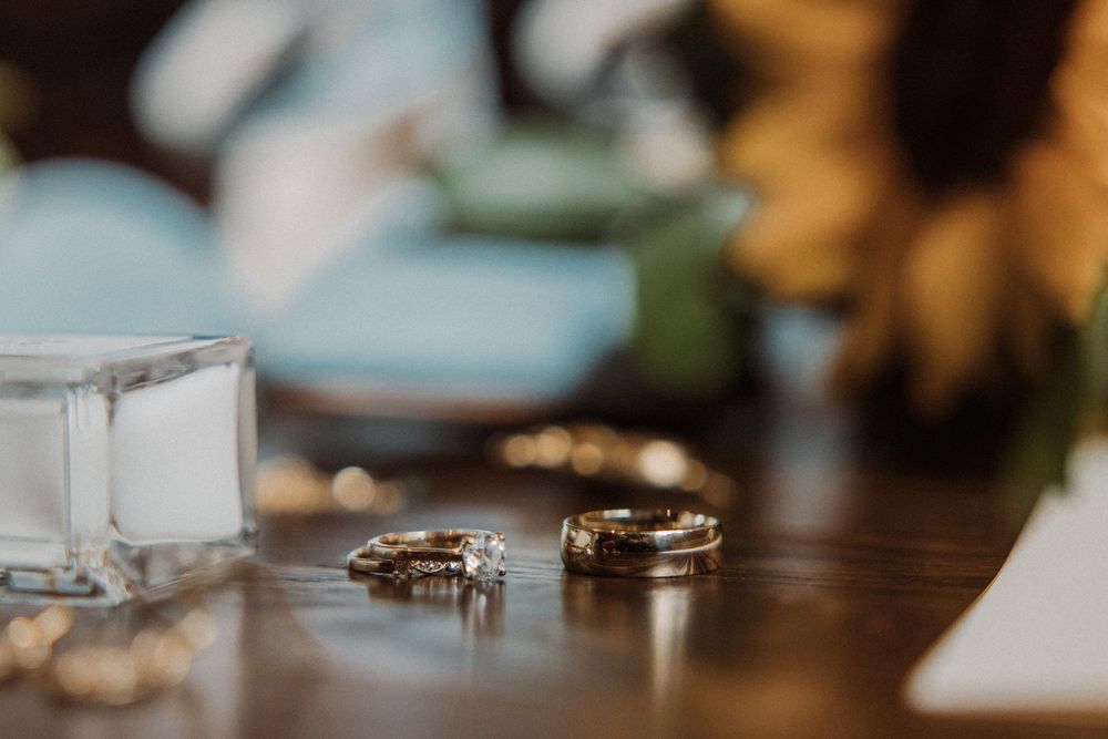 Close-up shot of three wedding rings resting on a wooden surface with soft bokeh lighting in the background.