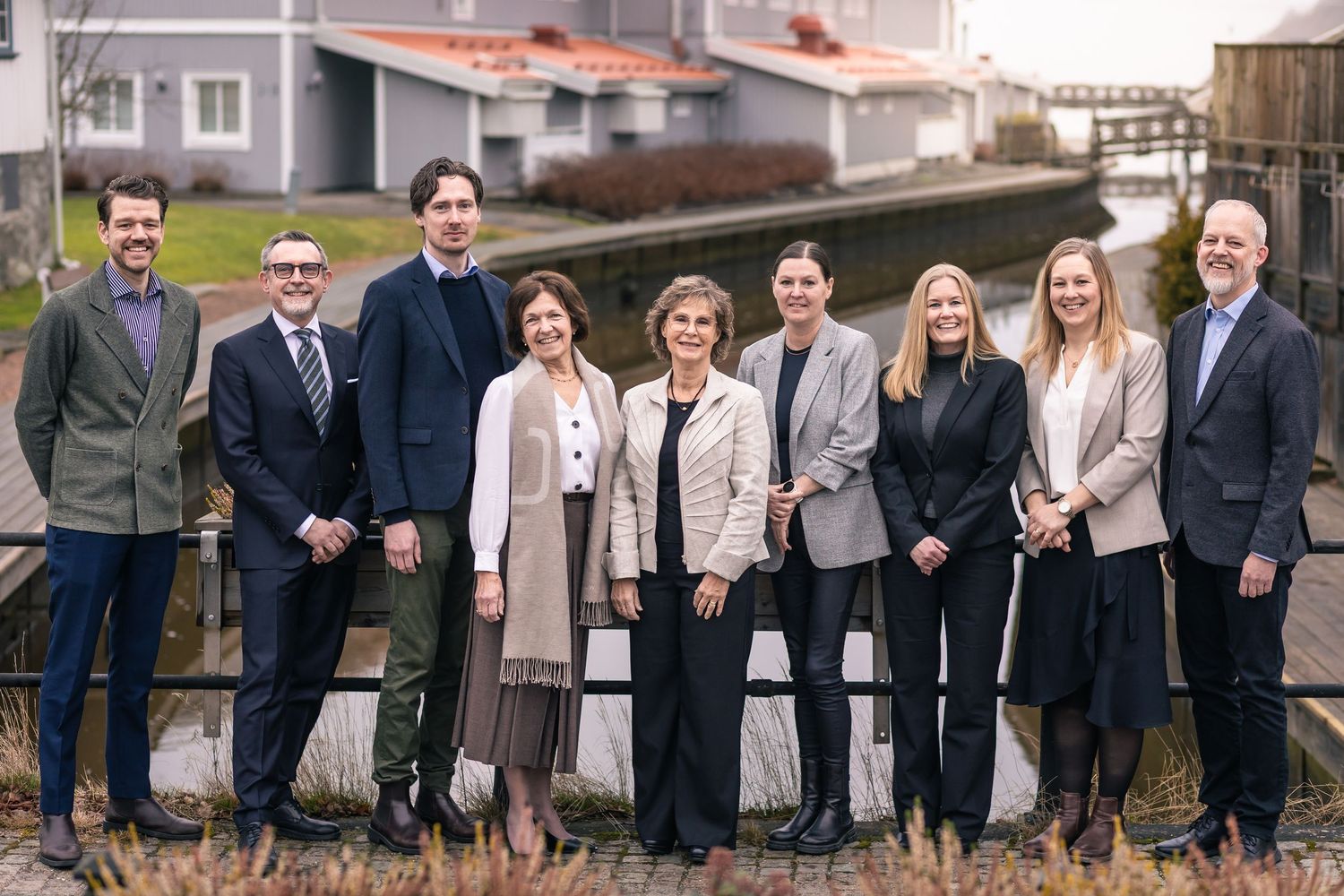 A group of business professionals standing together outdoors wearing blazers and formal attire for a corporate team photo.