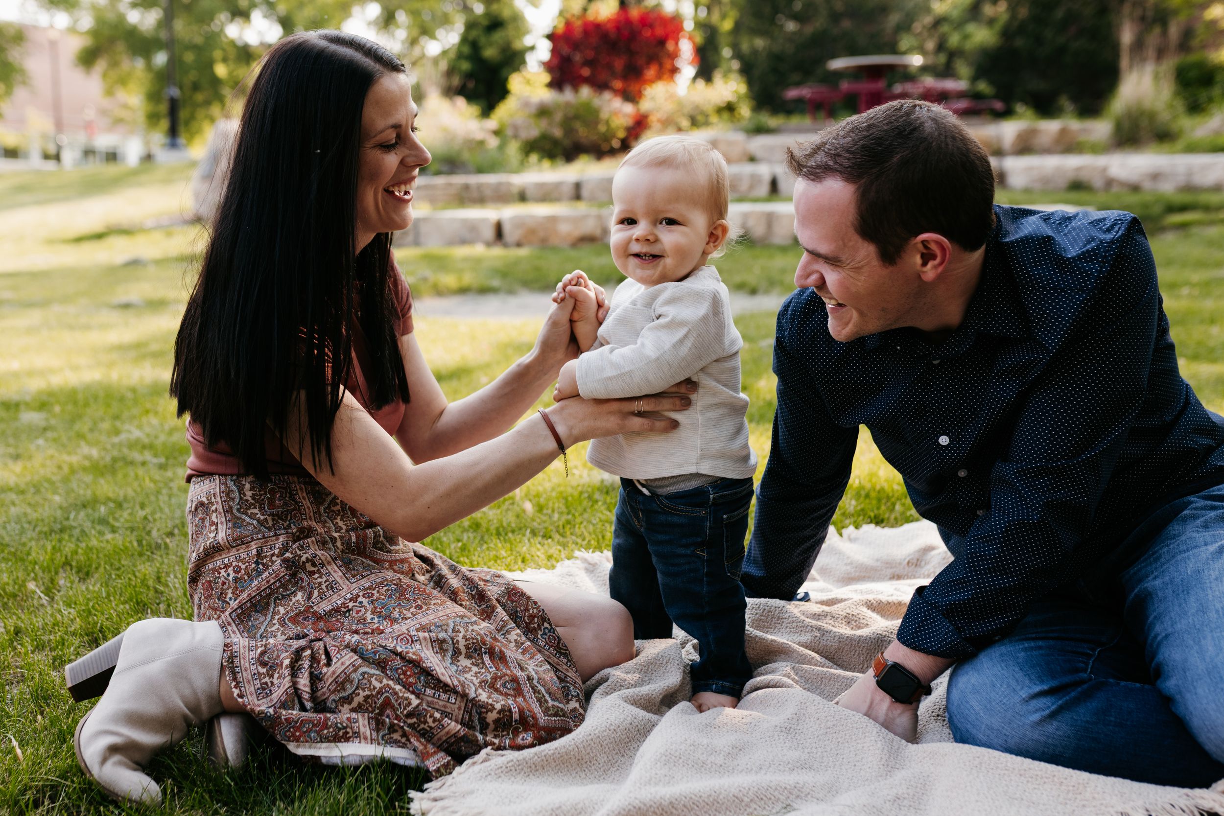 Young family enjoying a picnic together on a blanket in a sunny park on grass.