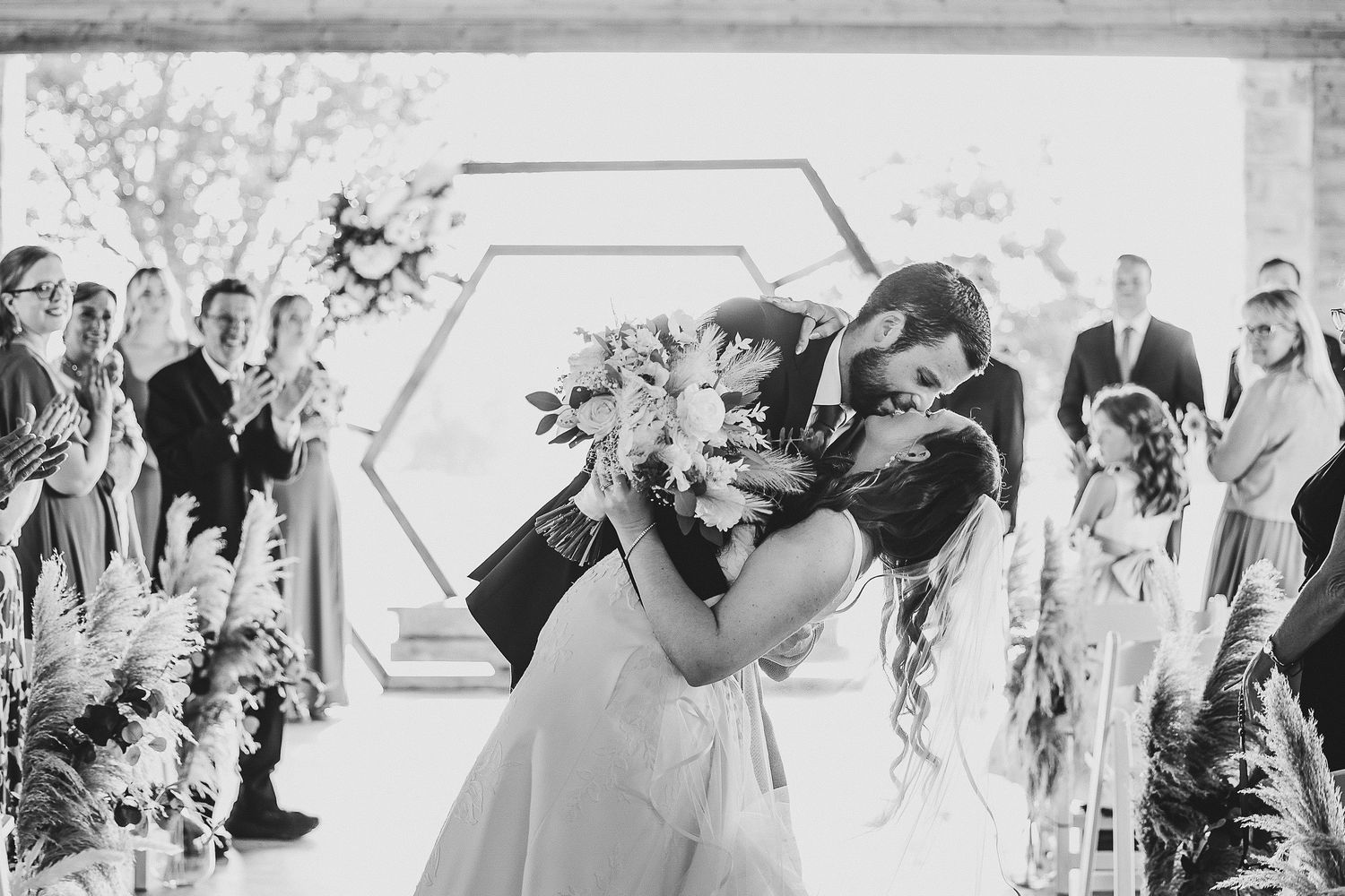 beautiful black and white photo of groom dipping his bride after their wedding ceremony for their first kiss