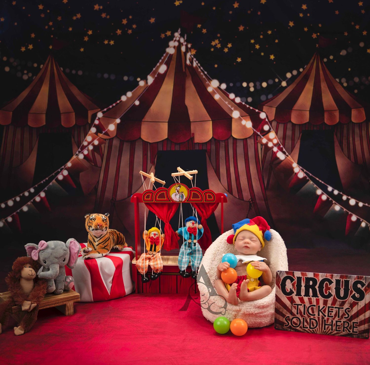 Vintage circus themed setup with striped tents, string lights, and decorative props on red carpet.