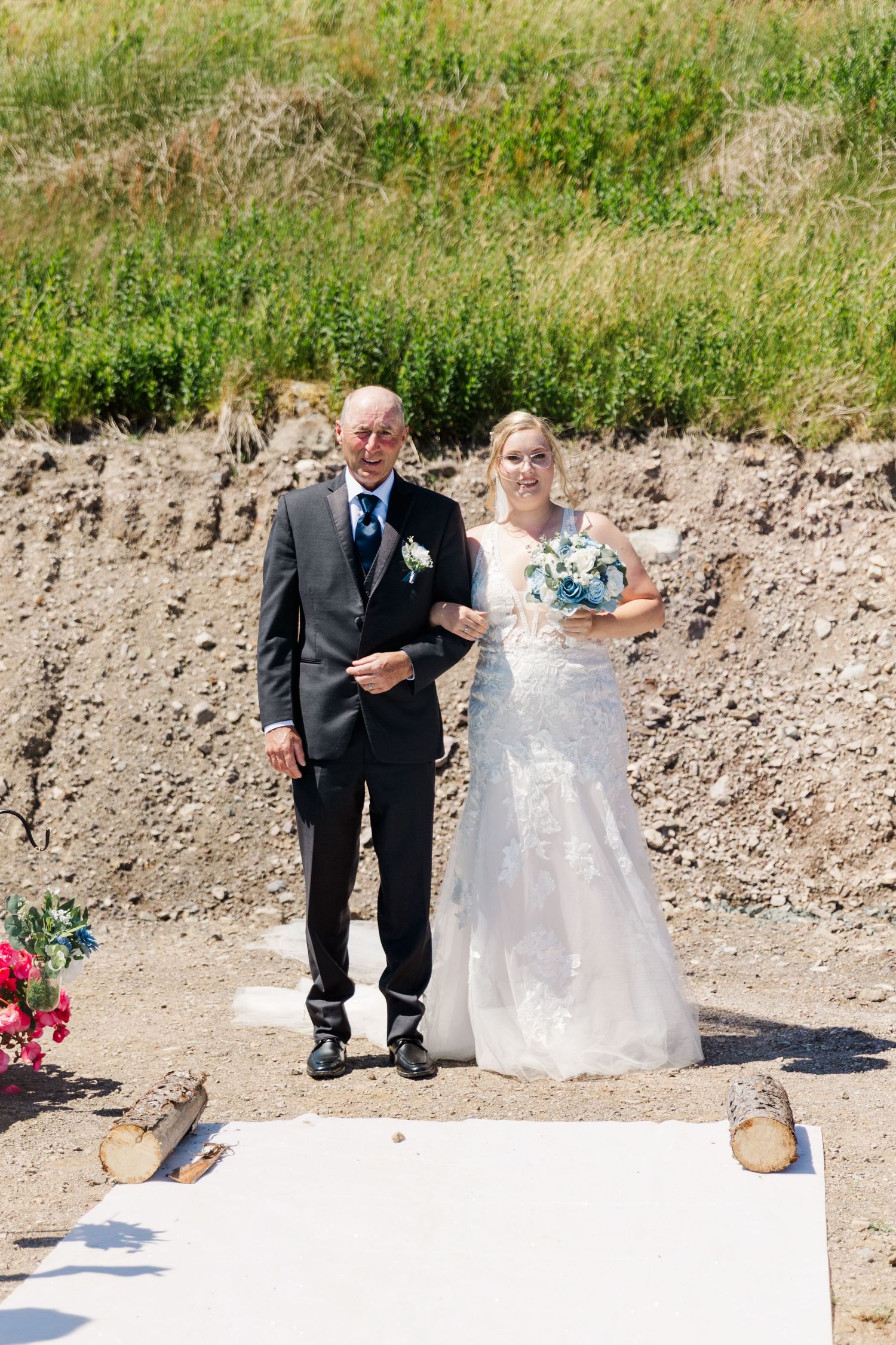 A wedding party on an outdoor sandy slope wearing formal attire on a sunny day.
