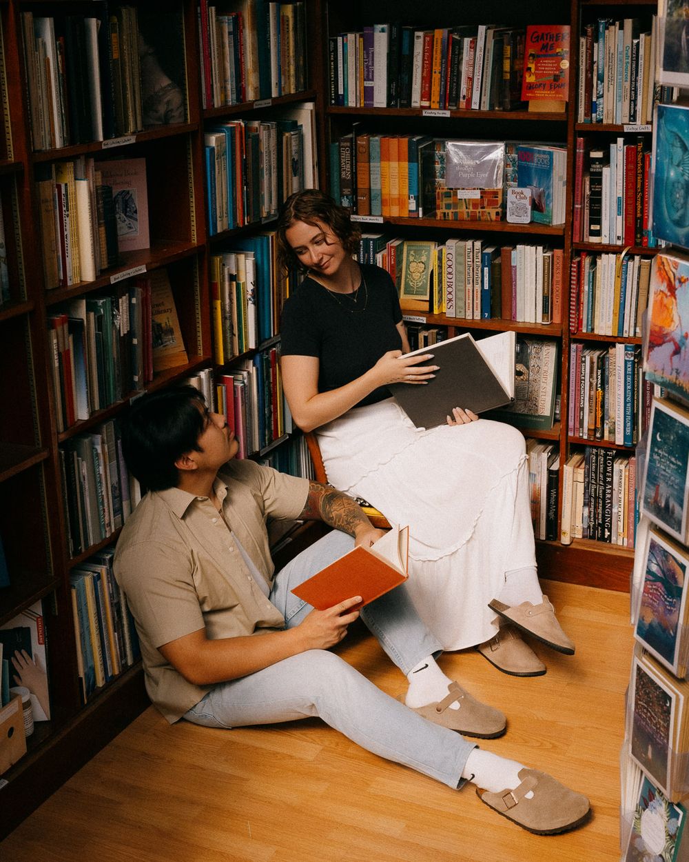 A man and woman reading books next to each other in a bookstore.