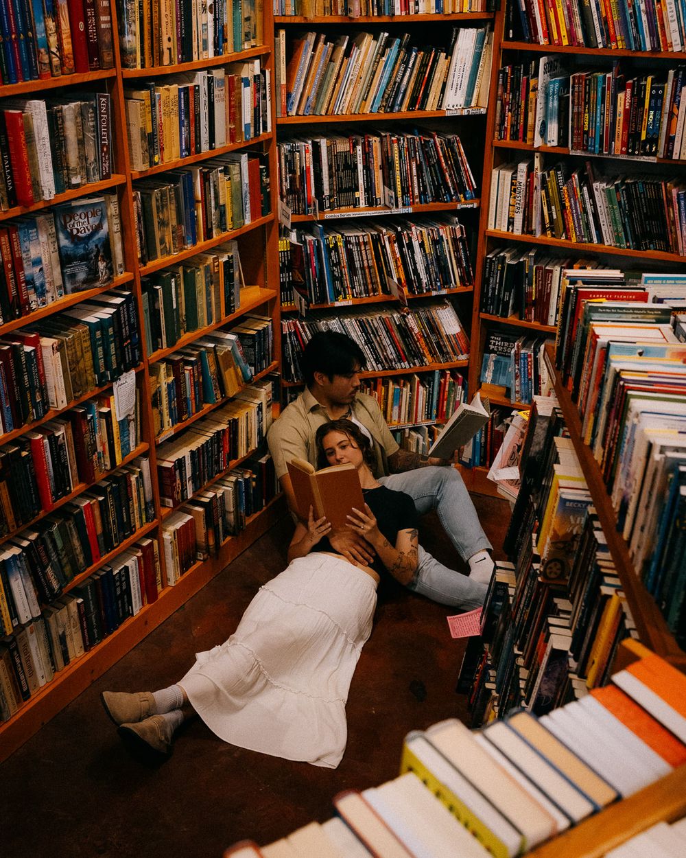 A couple laying on the floor reading in a bookstore.